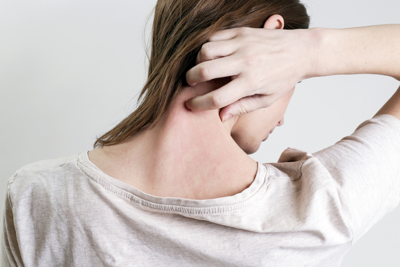 Close up view of woman scratching her neck.